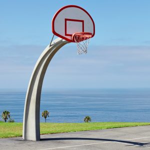 vertical shot of a basketball hoop near the sea under the beautiful blue sky
